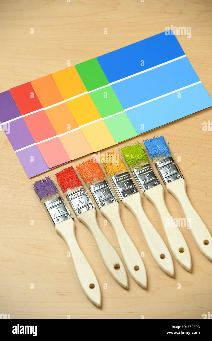PAintbrushes with different colors with paint samples on wooden table Stock Photo