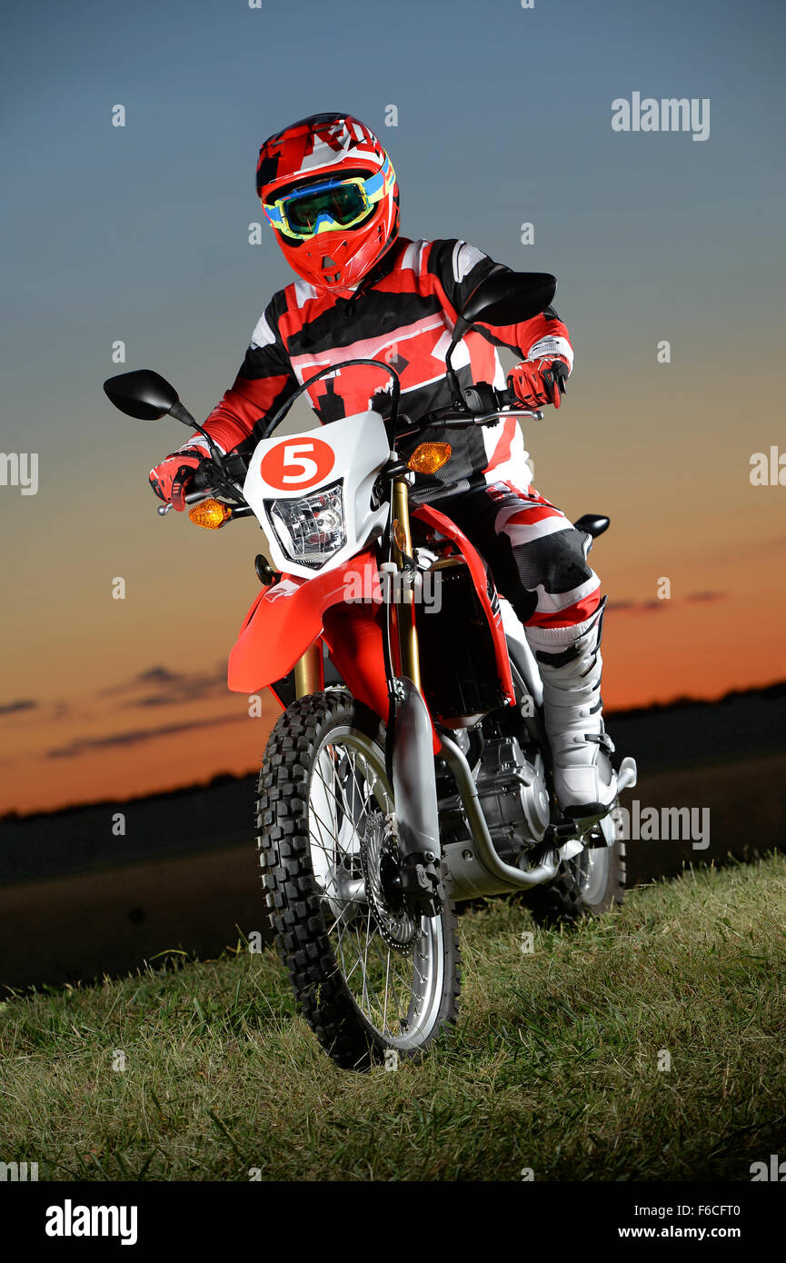 Man riding dirt bike at sunset over grassy area Stock Photo