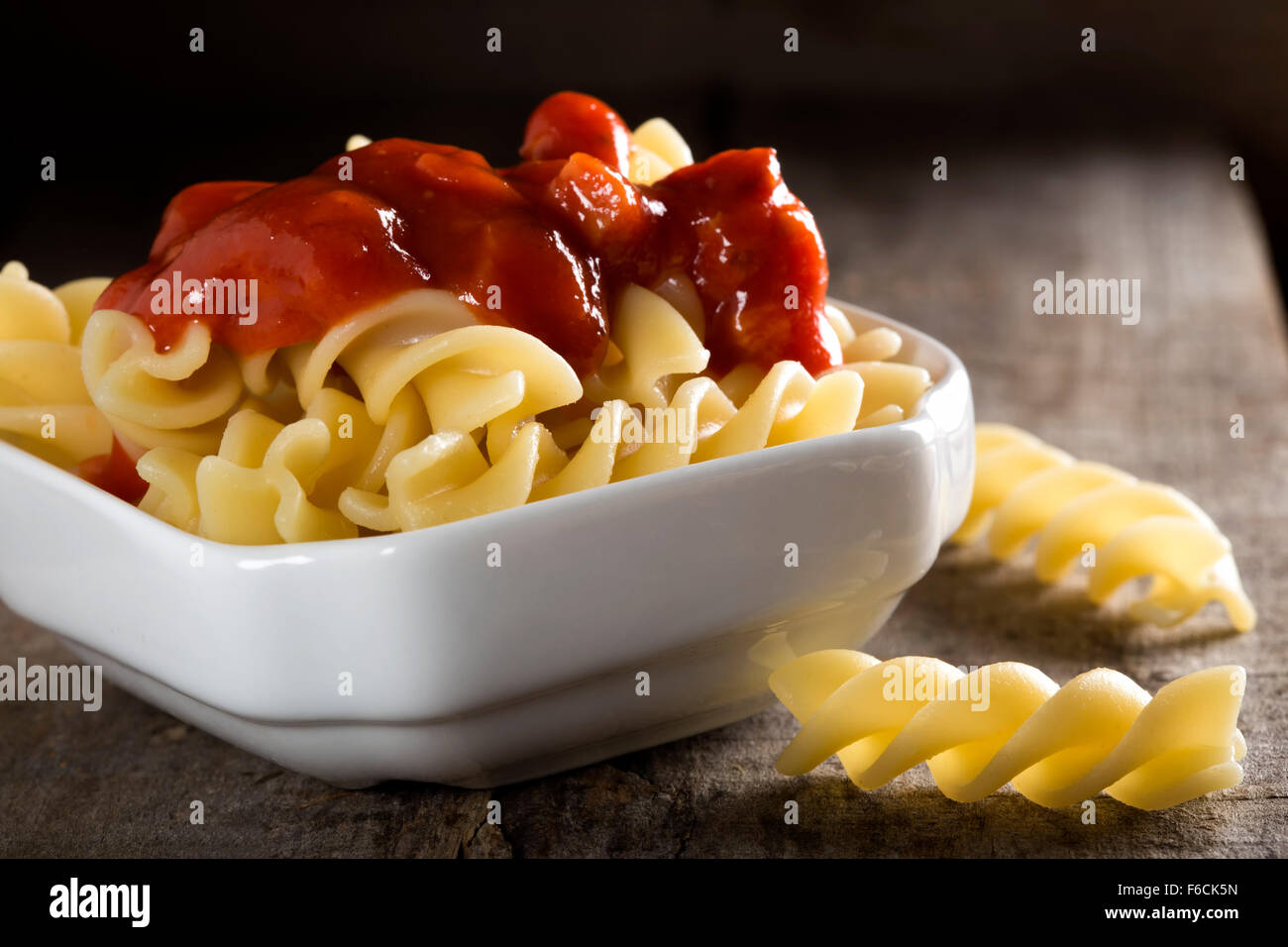 Boiled pasta and tomato sauce over wood background Stock Photo