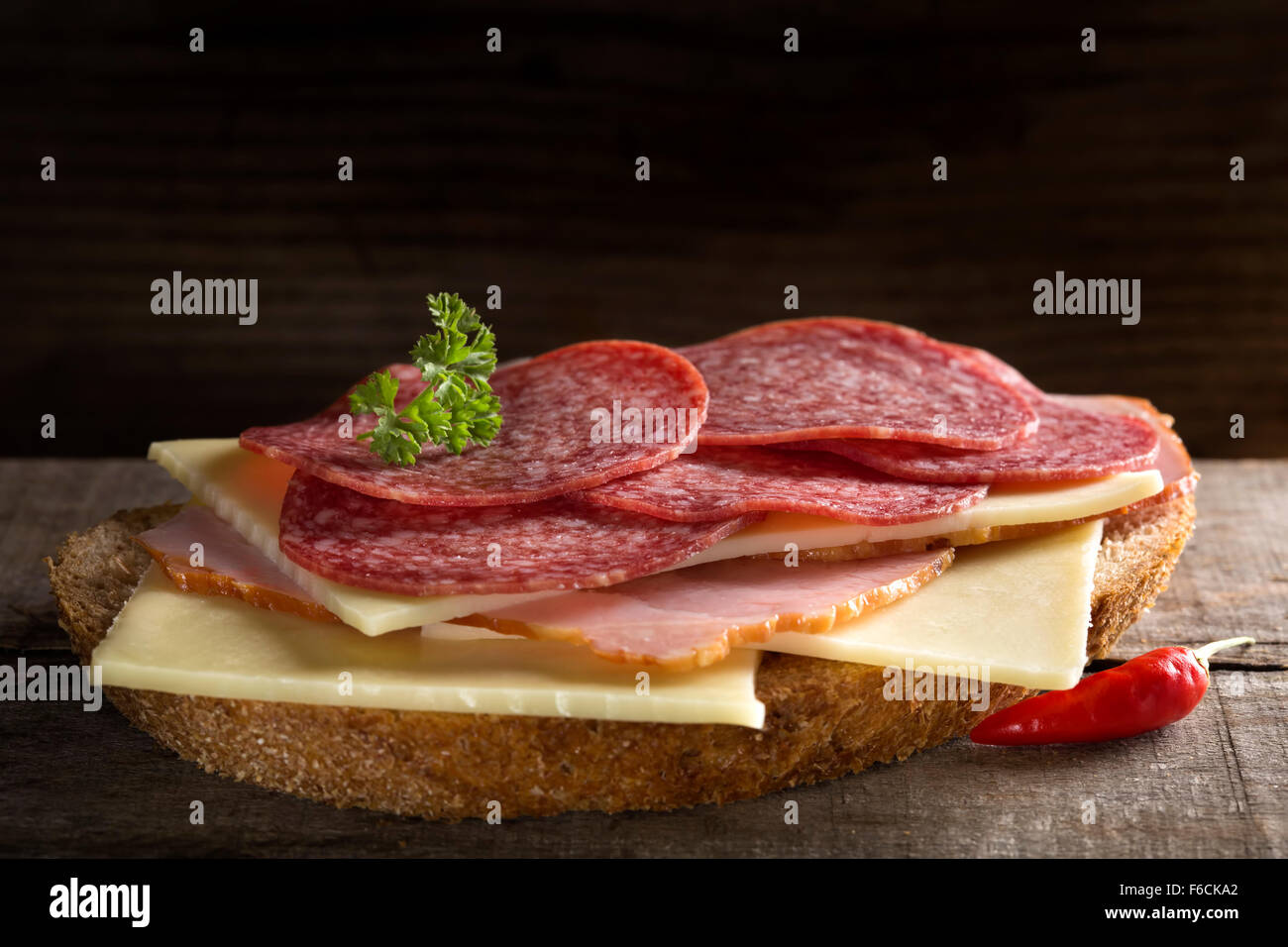 Open sandwich with ham, salami and cheese on wooden background Stock Photo