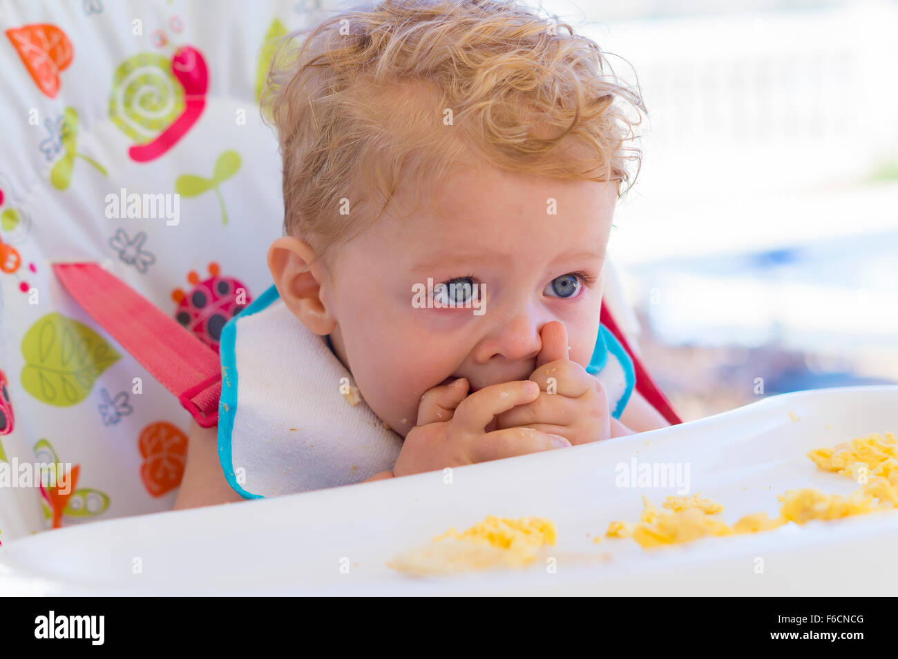 Gorgeous happy toddler eating food in high chair Stock Photo