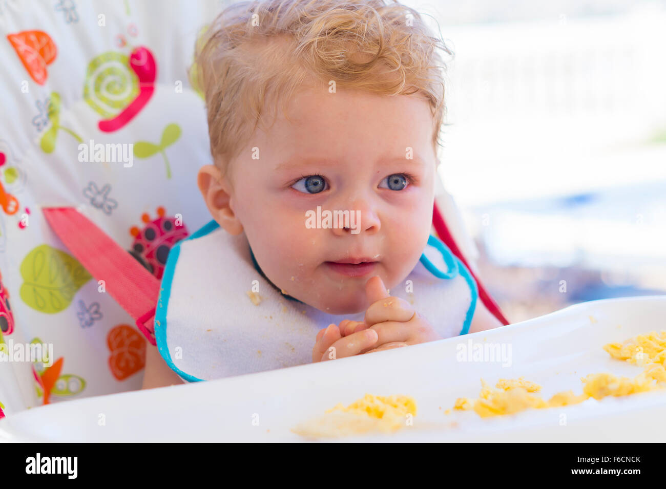 happy toddler eating food in high chair Stock Photo Alamy