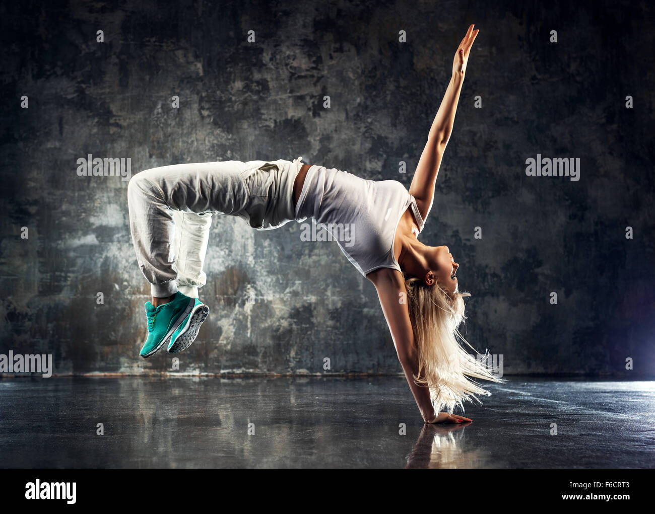 Young woman modern dancer. On dark stone wall background. Stock Photo