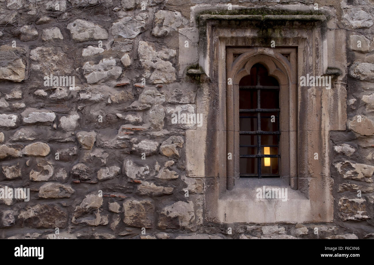 Monk's Window. A small window in an old wall of an abbey in the United Kingdom. A lamp burns inside. Stock Photo