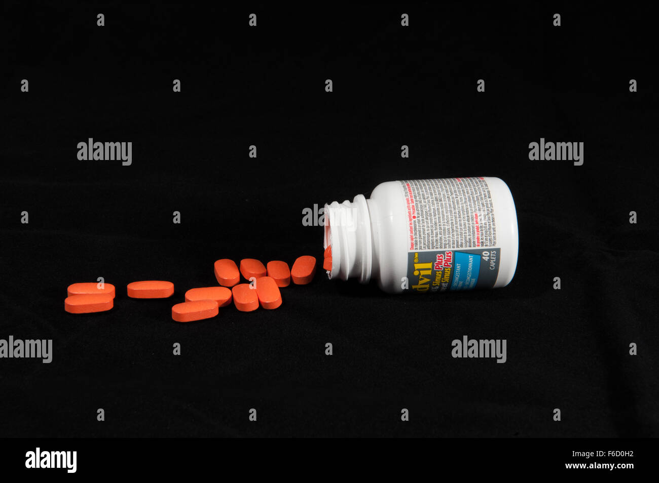 A container of Advil on it's side and spilled tablets Stock Photo