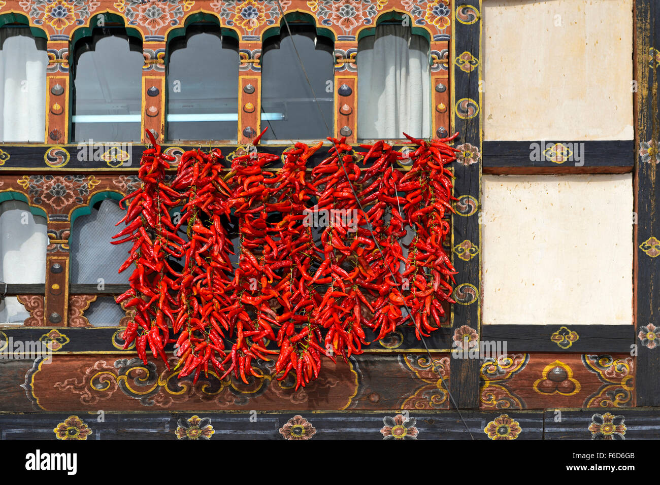 Red chili pepper pods hanging at a window for drying, Paro, Bhutan Stock Photo