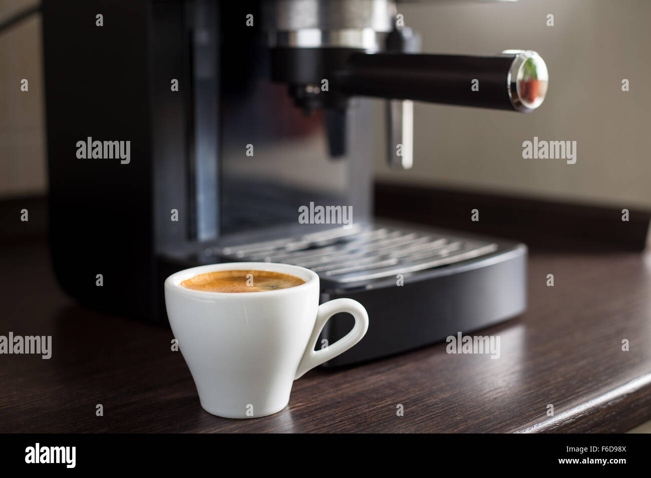 https://c8.alamy.com/comp/F6D98X/white-ceramic-cup-of-espresso-with-coffee-machine-on-the-table-brewing-F6D98X.jpg
