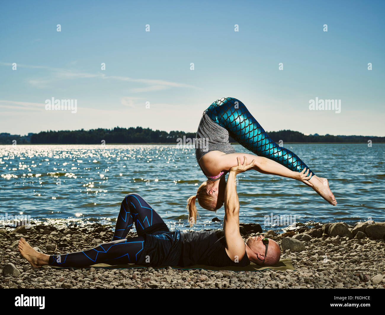 Sporty couple training acro yoga outdoors, summertime, sea and blue sky Stock Photo