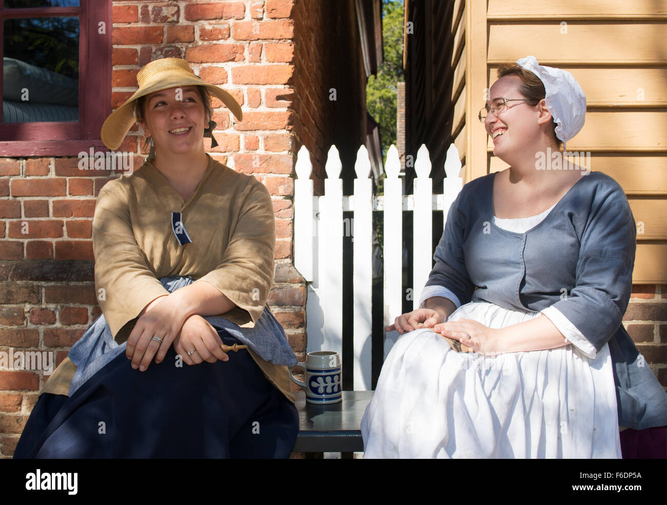 Two young smiling women in period costume at Colonial Williamsburg, Virginia, USA Stock Photo