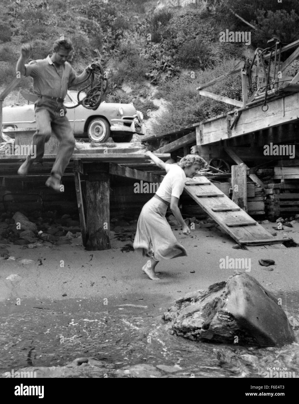 RELEASE DATE: March 30, 1953. MOVIE TITLE: Jeopardy. STUDIO: Metro-Goldwyn-Mayer (MGM). PLOT: The Stilwins are on vacation to an isolated beach in Mexico. Walking on a deserted jetty, Doug Stilwin gets his leg trapped under one of the logs. All attempts to move the log are futile and Helen Stilwin takes the car to get help. However, an escaped criminal kidnaps her. Will she be able to return to her husband before he drowns? PICTURED: BARBARA STANWYCK as Helen Stilwin and RALPH MEEKER as Lawson, the Fugitive. Stock Photo