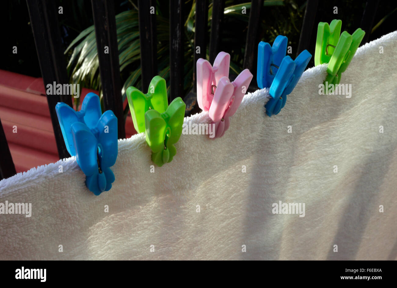 A white towel drying on a hotel balcony gripped with plastic clothes pegs Stock Photo