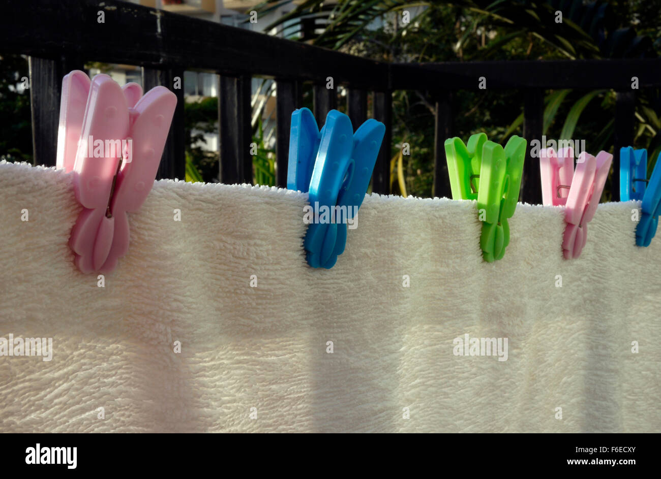 A white towel drying on a hotel balcony gripped with plastic clothes pegs Stock Photo