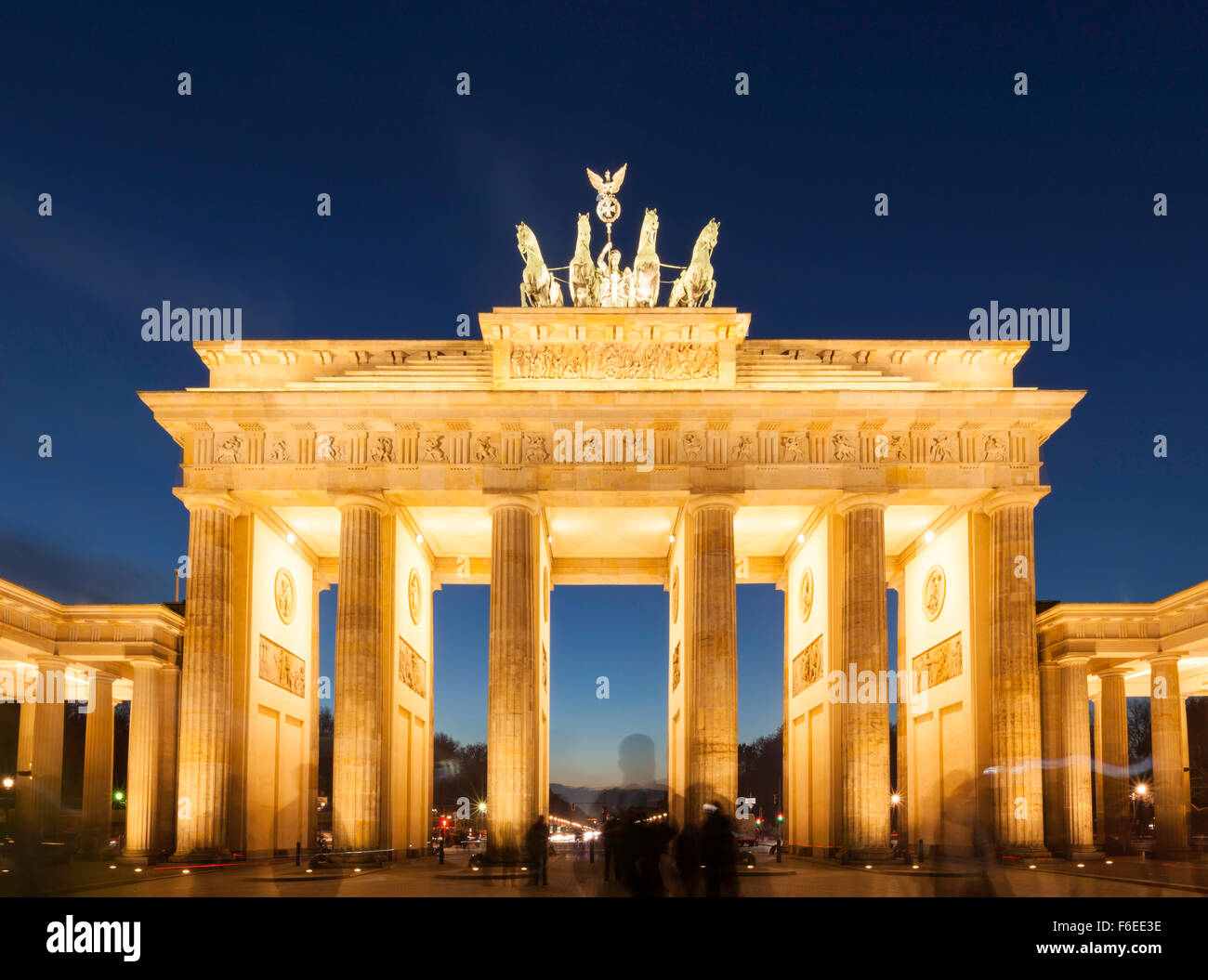 Berlin, illuminated Brandenburg Gate at dusk, long exposure shot with ghosted silhouettes of tourists in front Stock Photo