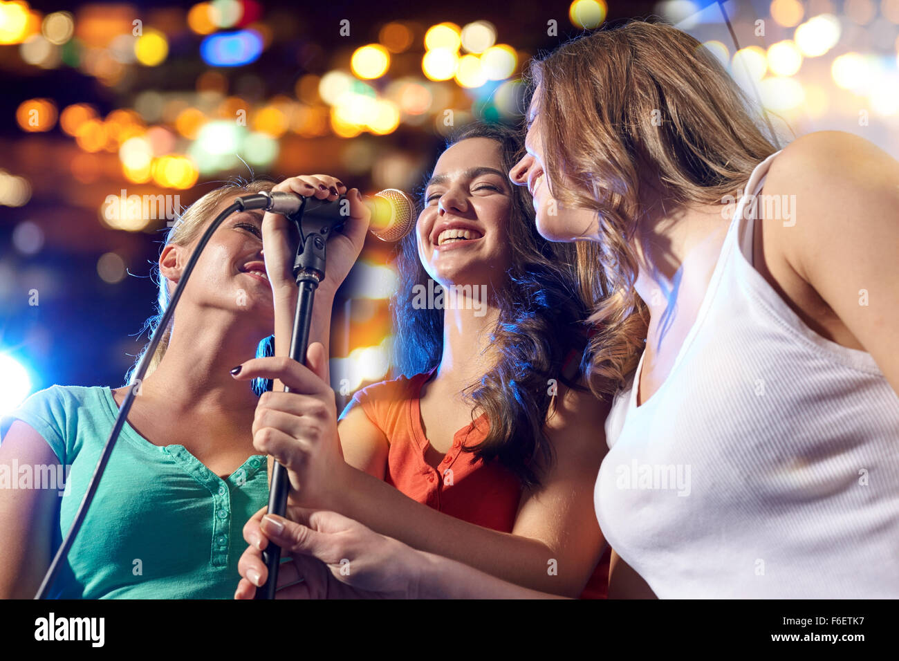 happy young women singing karaoke in night club Stock Photo