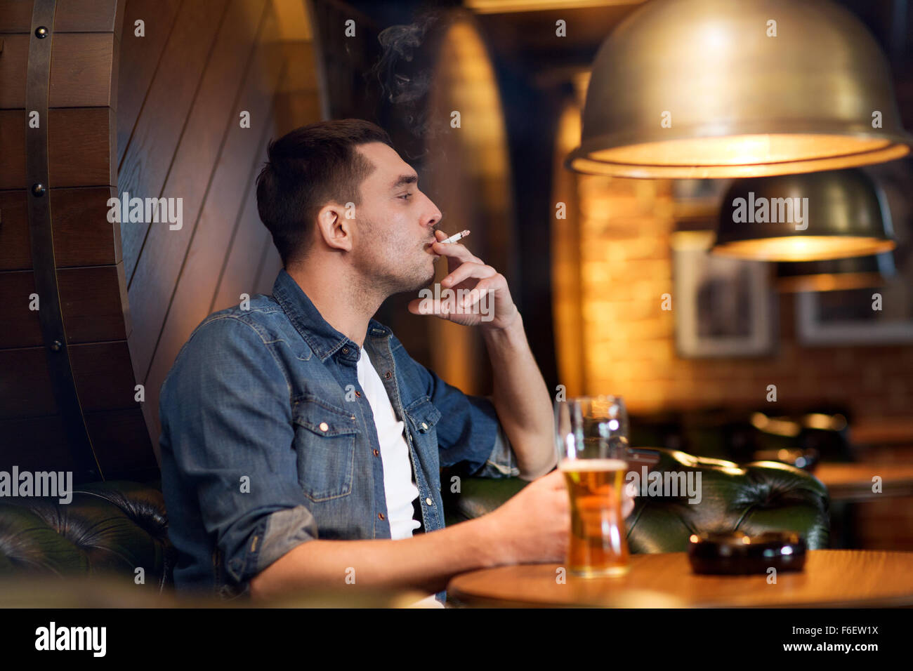 man drinking beer and smoking cigarette at bar Stock Photo - Alamy