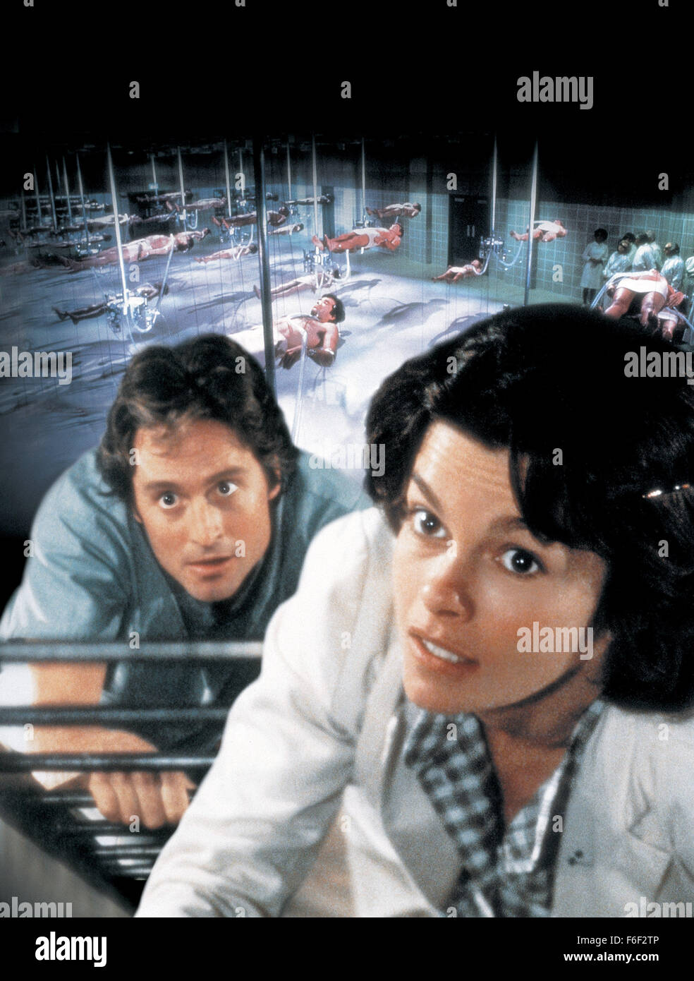 Jan 06, 1978; Los Angeles, CA, USA; Key poster art featuring MICHAEL DOUGLAS as Dr. Mark Bellows and GENEVIEVE BUJOLD as Dr Susan Wheeler in the mystery thriller film 'Coma' directed by Michael Crichton. Stock Photo