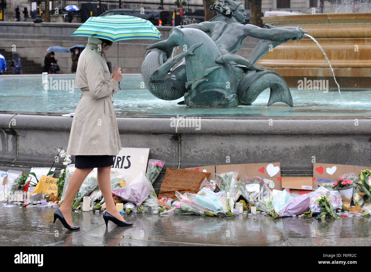 London, UK. 17th November, 2015. A stylishly dressed women reflects at the tribute to those killed in the Paris massacre at the fountain on Trafalgar Square. The heavy rain which the rest of the country has been experiencing reaches London. Credit:  JOHNNY ARMSTEAD/Alamy Live News Stock Photo