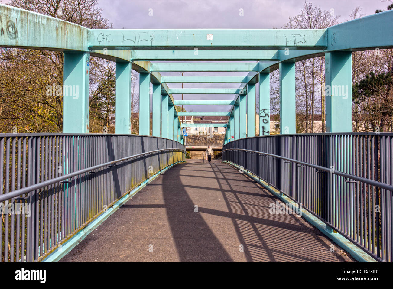 person crossing a steel bridge in Livingston West Lothian Stock Photo