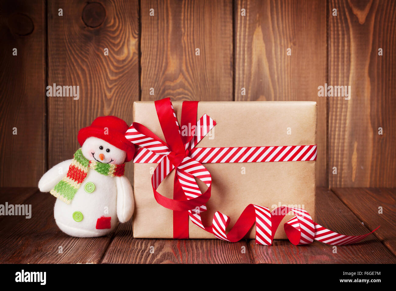 Christmas gift box and snowman toy on wooden table Stock Photo