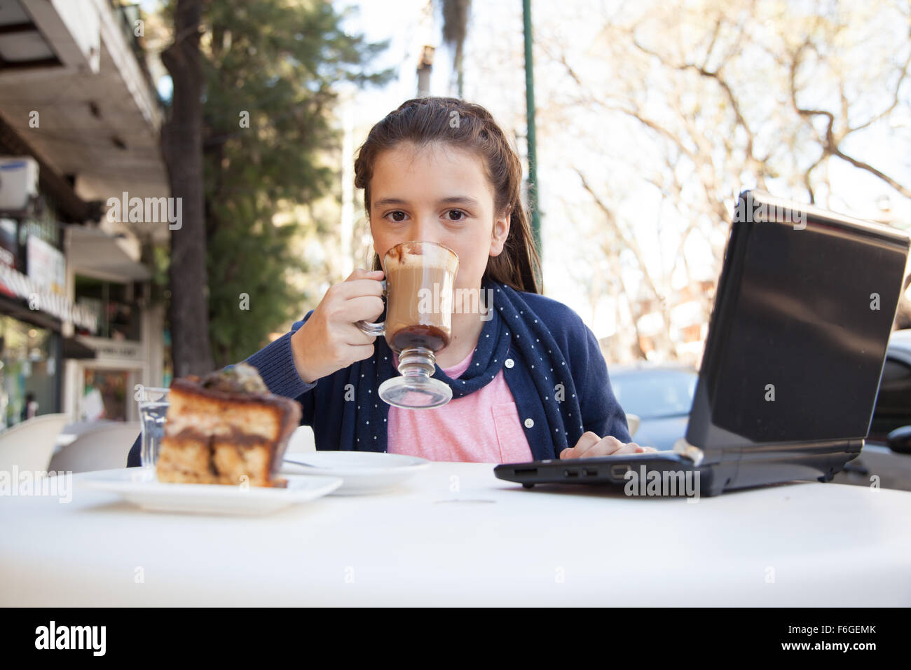 Girl using the computer while she drinks coffee Stock Photo