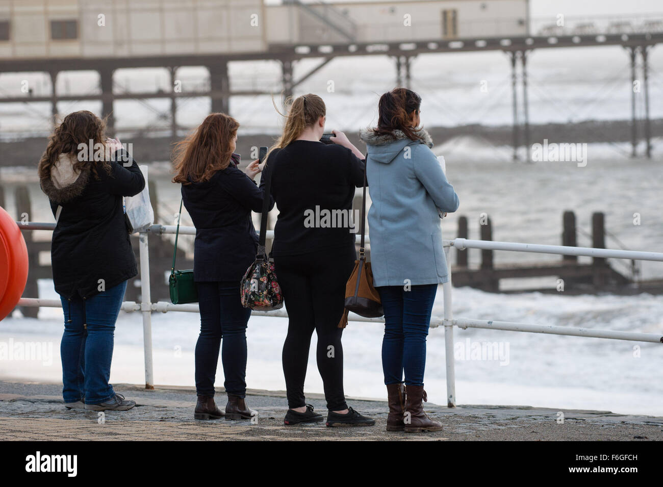 Aberystwyth Wales Uk, Tuesday 17 November 2015  UK weather: A group of young women photograph the waves as the second named storm of the season - Storm Barney - hits Aberystwyth on the west coast of Wales.    Gusts of wind were expected to reach 80mph over high ground, and heavy rain likely to cause  flooding in areas already saturated after days of rainfall    photo Credit:  Keith Morris / Alamy Live News Stock Photo