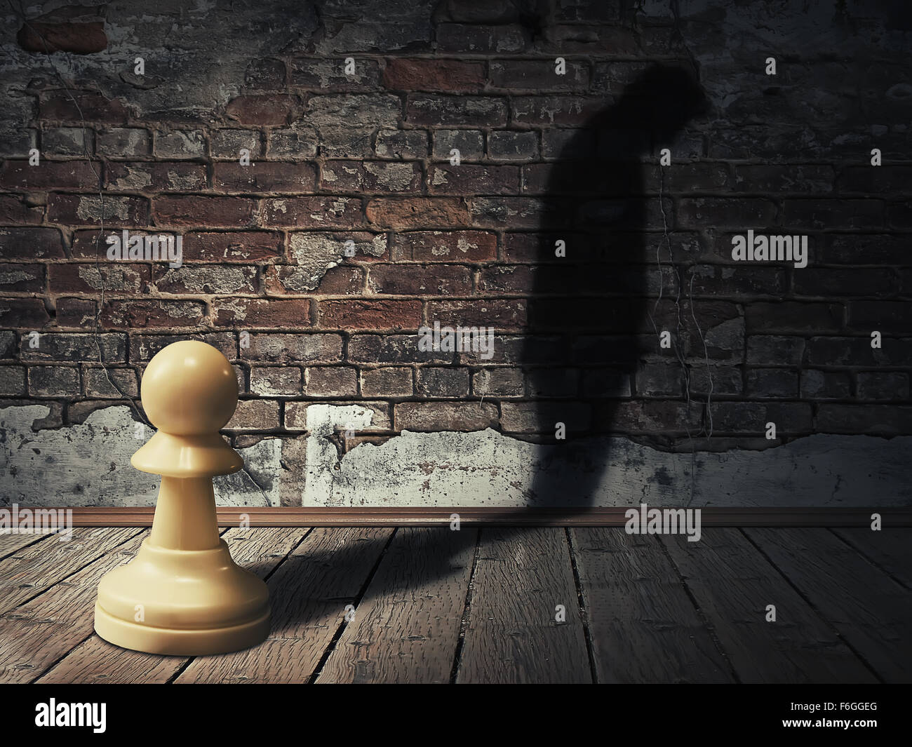 A white pawn piece into a dark room with its man silhouette shadow on a brick wall Stock Photo