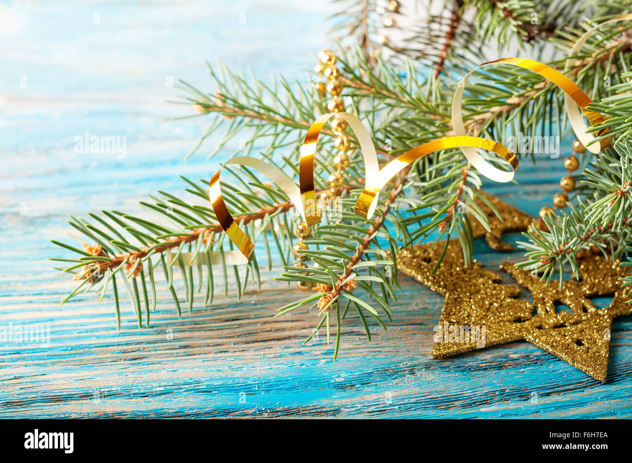 Golden Christmas decorations and fir branch on a blue wooden background ...