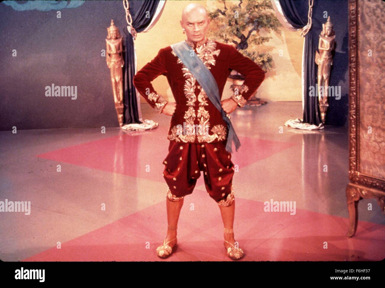1956, Film Title: KING AND I, Director: WALTER LANG, Studio: FOX, Pictured: 1956, AWARDS - ACADEMY, BEST ACTOR, YUL BRYNNER, WALTER LANG, ROYAL, ORIENTAL, EXOTIC, BALD HEAD, GOLD, HANDS ON HIPS, MENACING, THREATENING, STERN, AUTHORITY FIGURE, KING, RULER, LEADER, OSCAR (MOVIE), RED. (Credit Image: SNAP) Stock Photo