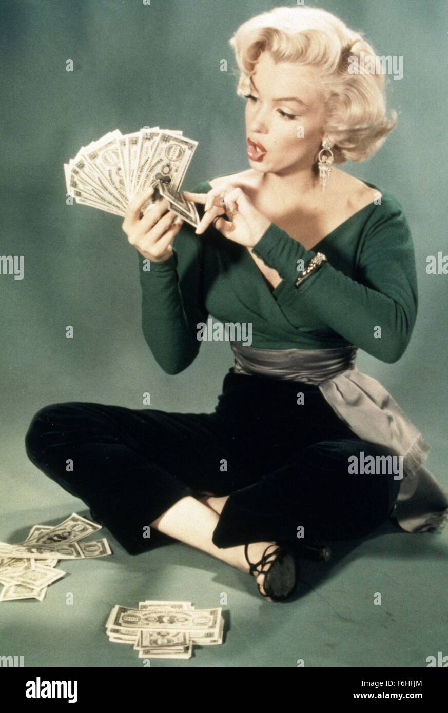 1953, Film Title: HOW TO MARRY A MILLIONAIRE, Director: JEAN NEGULESCO, Studio: FOX, Pictured: MARILYN MONROE, PORTRAIT, COUNTING, MONEY, GREEDY, STUDIO, GREEN, SITTING, CROSS LEGGED, AMAZED, SURPRISED, EXCITED, BOMBSHELL, BLONDE. (Credit Image: SNAP) Stock Photo
