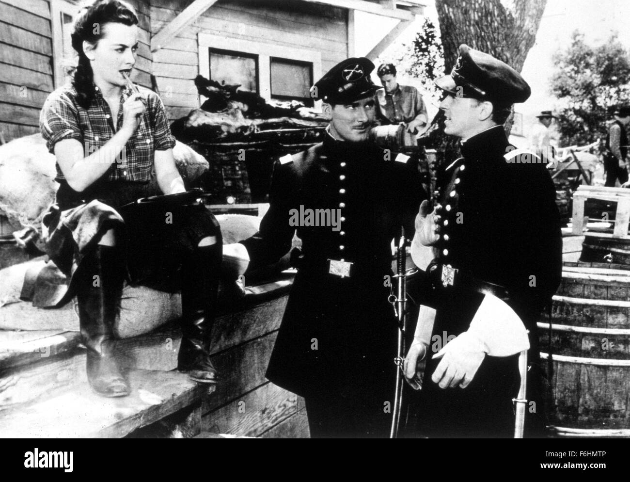 1940, Film Title: SANTA FE TRAIL, Director: MICHAEL CURTIZ, Studio: WARNER, Pictured: MICHAEL CURTIZ, OLIVIA DeHAVILLAND, ERROL FLYNN, RONALD REAGAN, CHECKED SHIRT, FLANNELETTE, BOOTS, SOLDIERS, MILITARY UNIFORM, SITTING, CHEWING, FLIRTING, DISINTERESTED, BOY MEETS GIRL, WOMEN (BUTCH), WOMEN (MASCULINE), WOMEN (TOMBOY). (Credit Image: SNAP) Stock Photo
