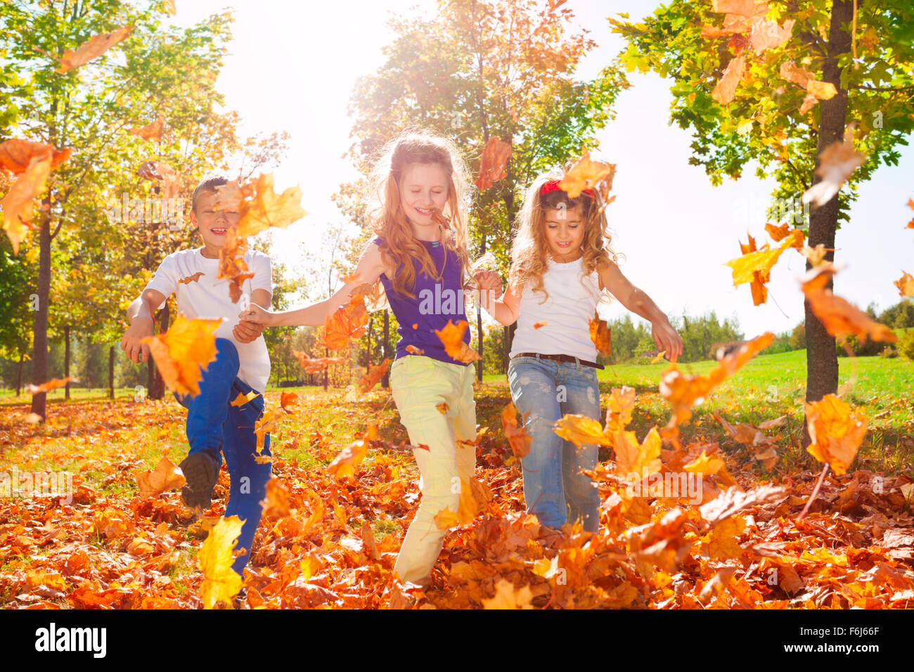 Happy friends play with colorful leaves in forest Stock Photo - Alamy
