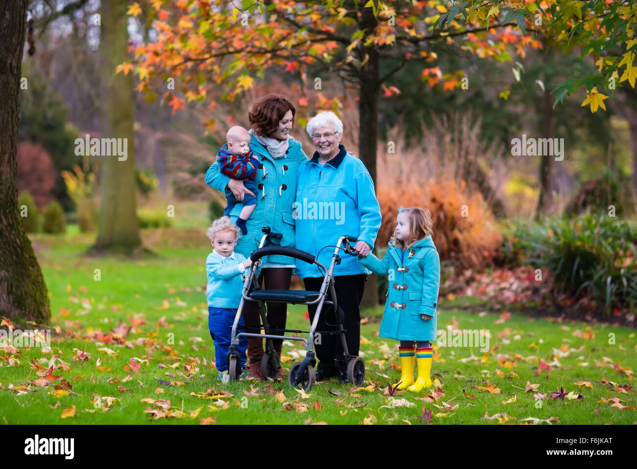 Happy senior lady with a walker or wheel chair and children. Grandmother and kids enjoying a walk in the park. Stock Photo