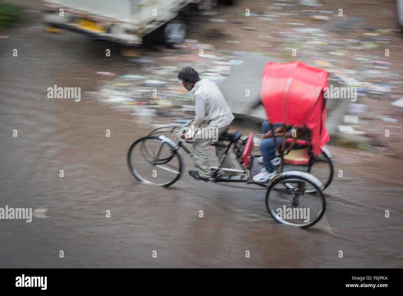 Bicycle rickshaw pedaling through flooding in the streets (Jaipur, India). Stock Photo
