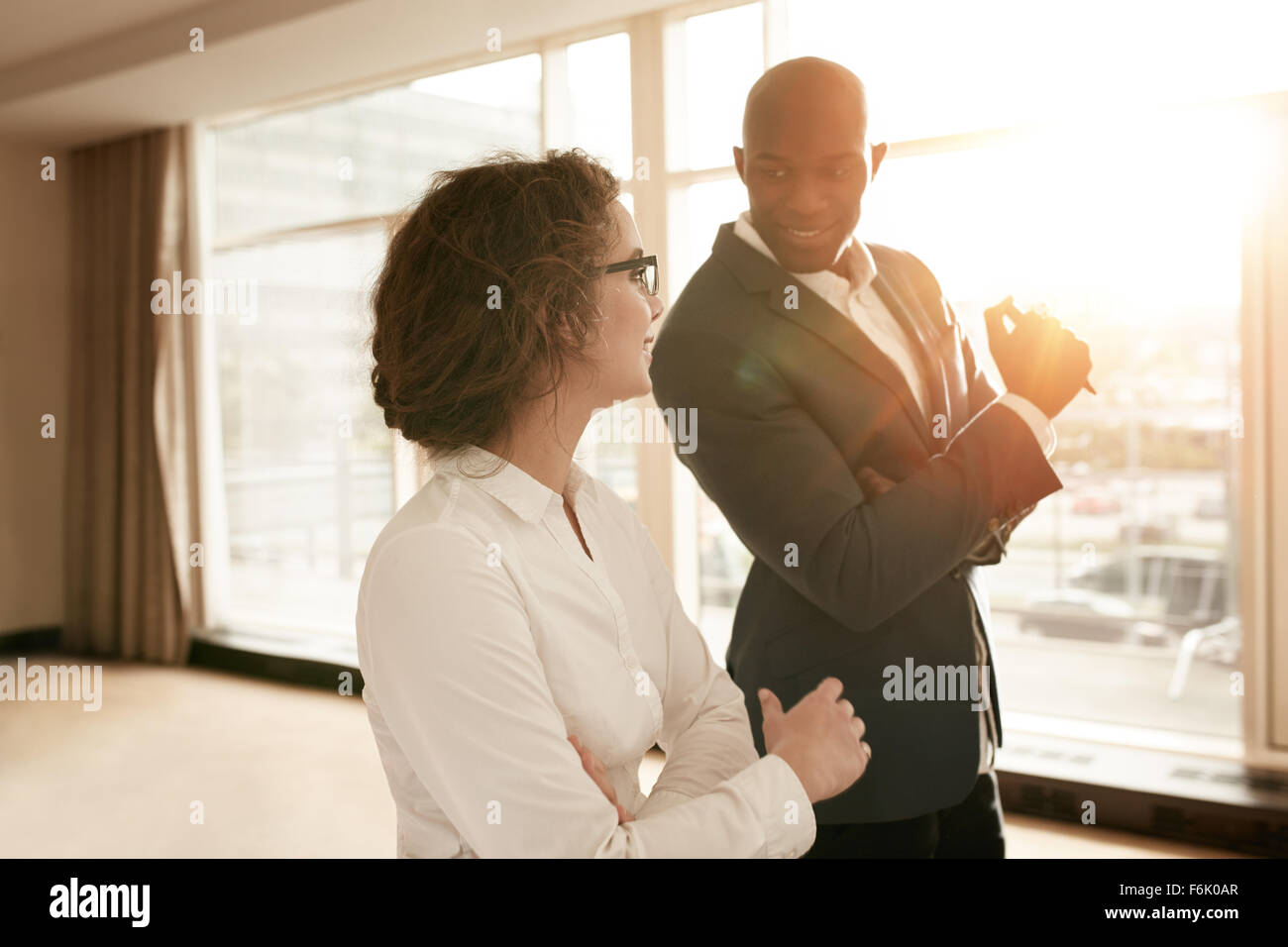 Two young business people discussing work during a business presentation in conference room at a hotel. Smiling business people Stock Photo