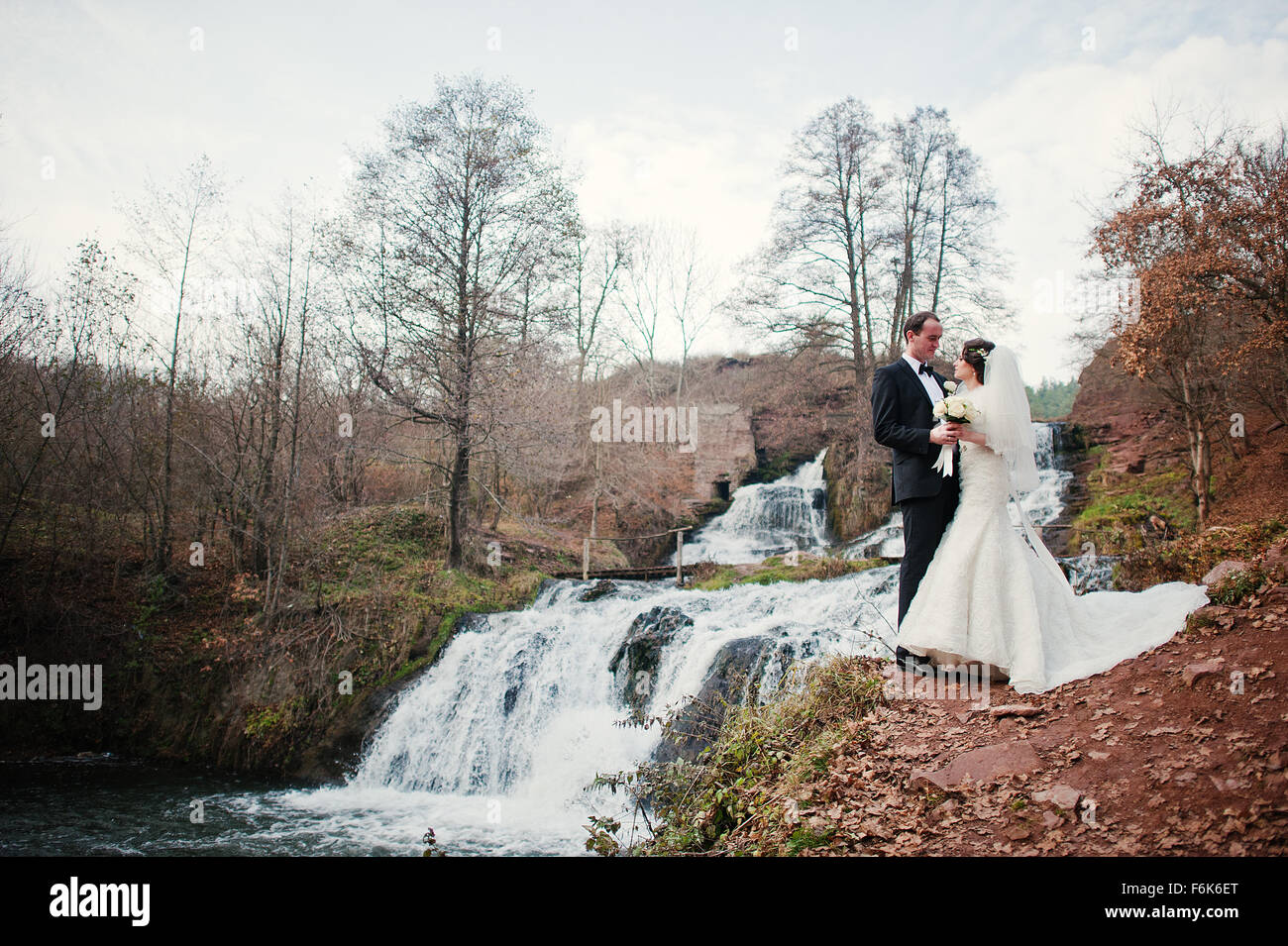 lovely newlyweds background waterfall at cold autumn day Stock Photo ...