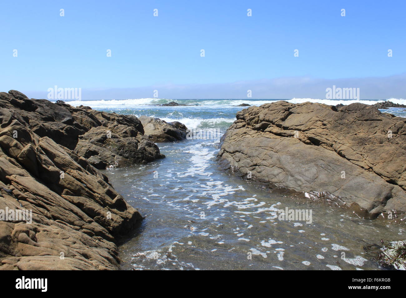 Wave Passing Between Two Rocks Waves moving in between rocks . Fog and waves in the back ground . One ...