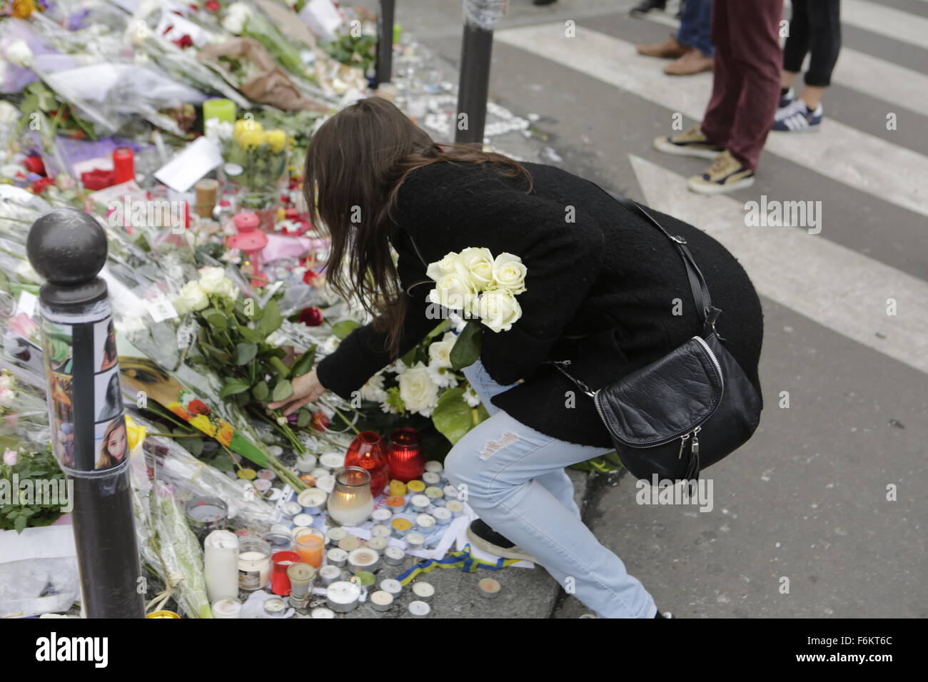 Paris, France. 17th November 2015. A woman places flowers at the memorial outside the restaurant Le Petit Cambodge for the people killed here during the Paris attacks. Parisians and tourists continue to visit the memorials for the people killed in the terrorists attacks in Paris, to lay down flowers and candles and to pay their respect. Over 130 people have been by terrorist from the Islamic State. Stock Photo