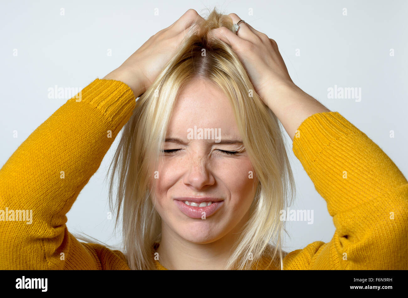 Close up Young Woman Scratching her Head Using Two Hands, Showing Disgusted Facial Expression, Against Light Gray Background. Stock Photo