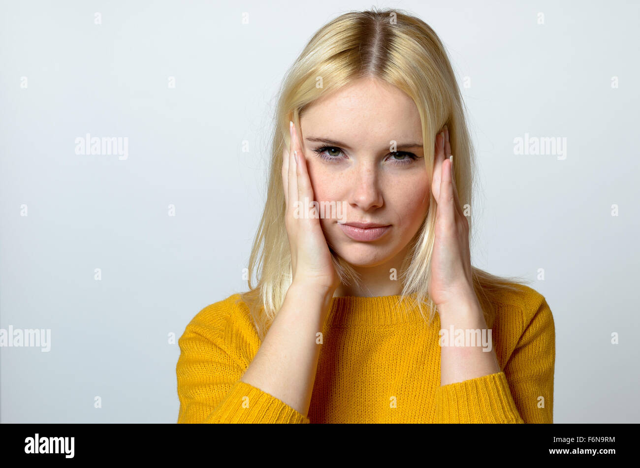 Close up Pretty Blond Young Woman with headache Looking at the Camera Against Gray Background. Stock Photo