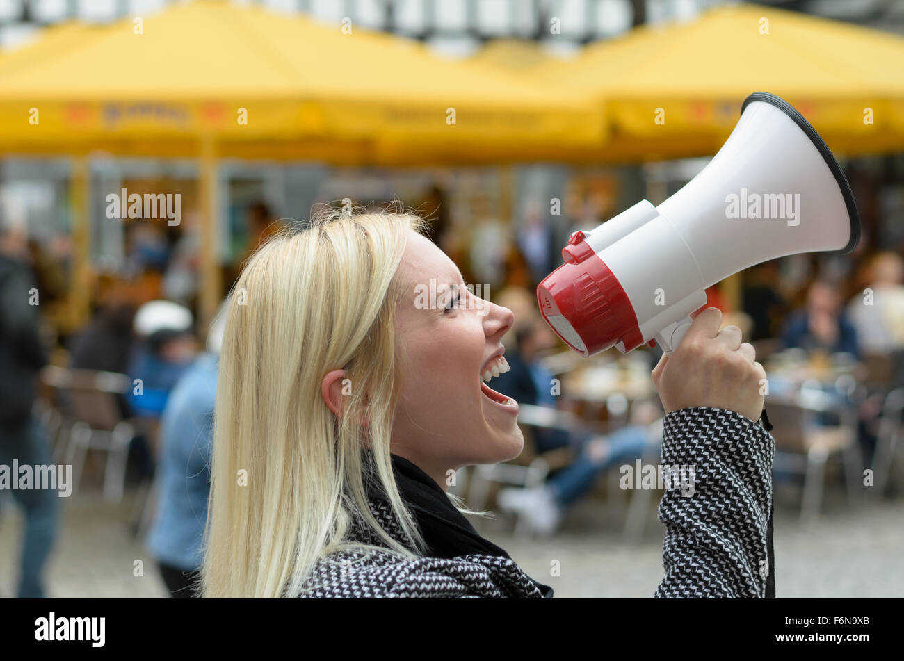 Woman yelling into a megaphone on an urban street voicing her displaeasure during a protest or demonstration, close up side view Stock Photo