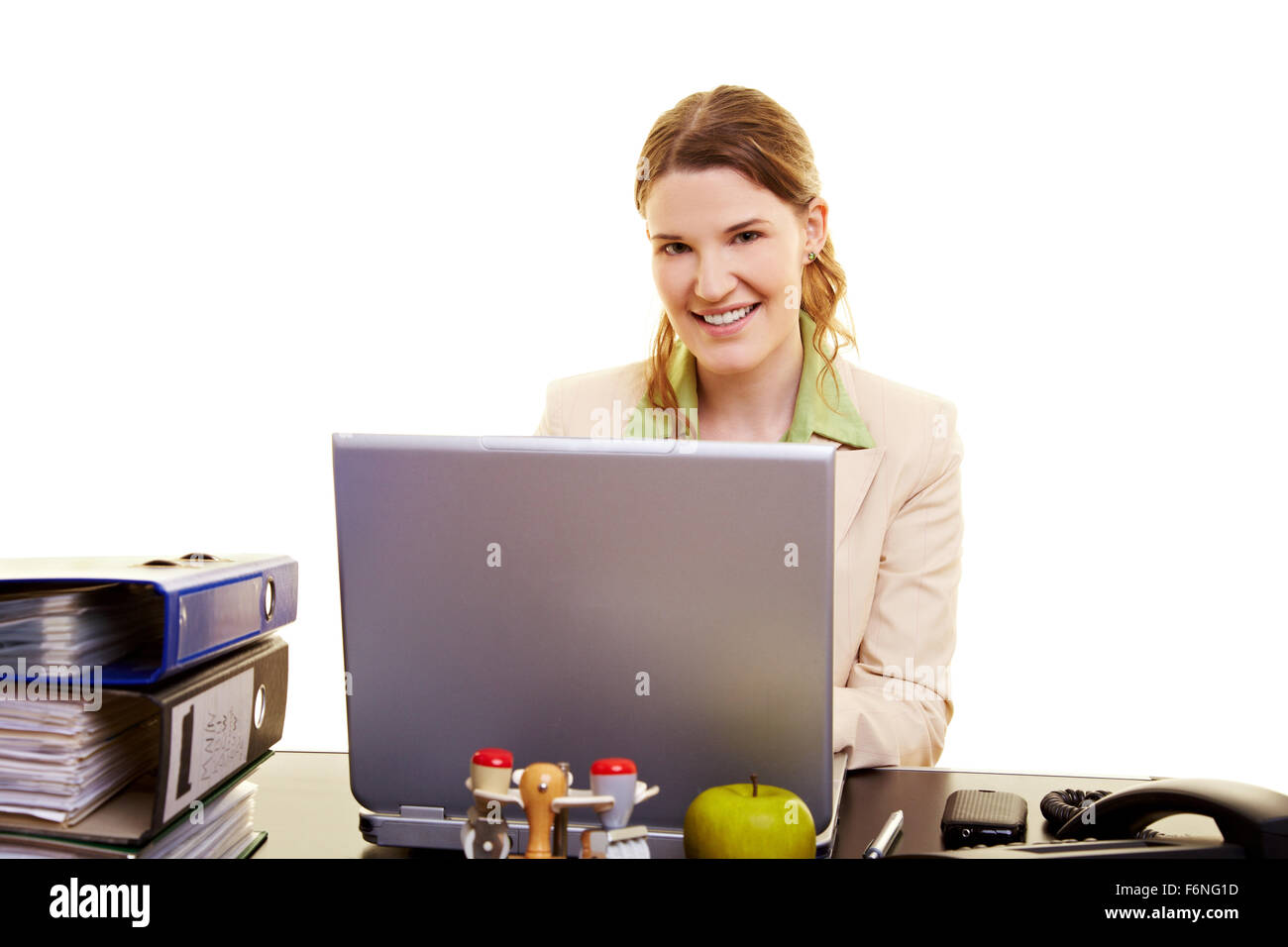 Smiling woman sitting at her desk with a laptop Stock Photo