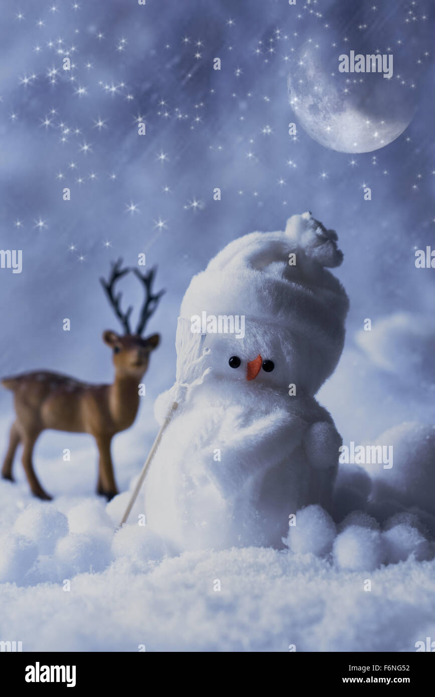 Snowman figure at night below a starry sky with reindeer in the ...