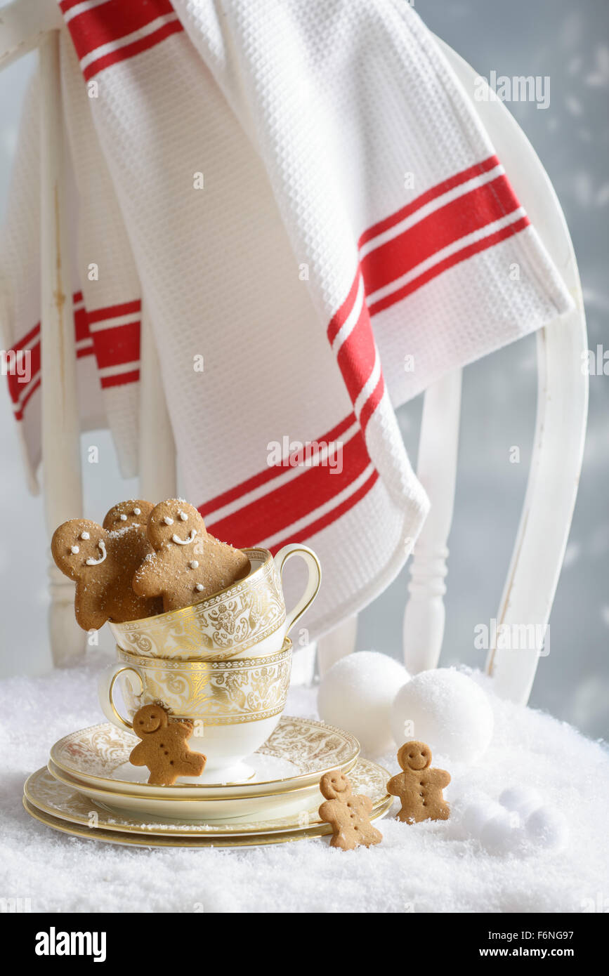 Freshly baked gingerbread men sitting in vintage teacups on festive chair Stock Photo