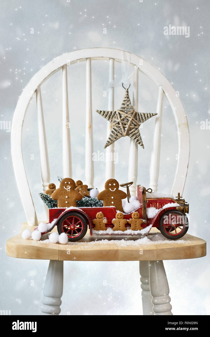 Festive Christmas gingerbread men sitting in vintage red truck with snow Stock Photo