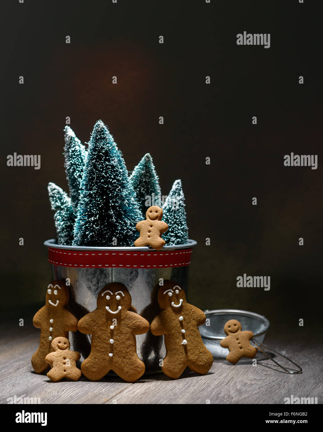 Low key image of homemade gingerbread family with Christmas trees Stock Photo