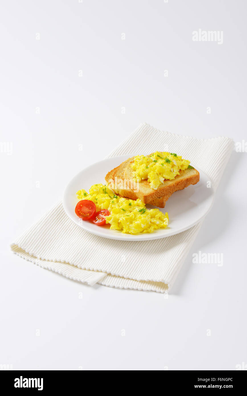 plate of scrambled eggs and slices of bread on white place mat Stock ...