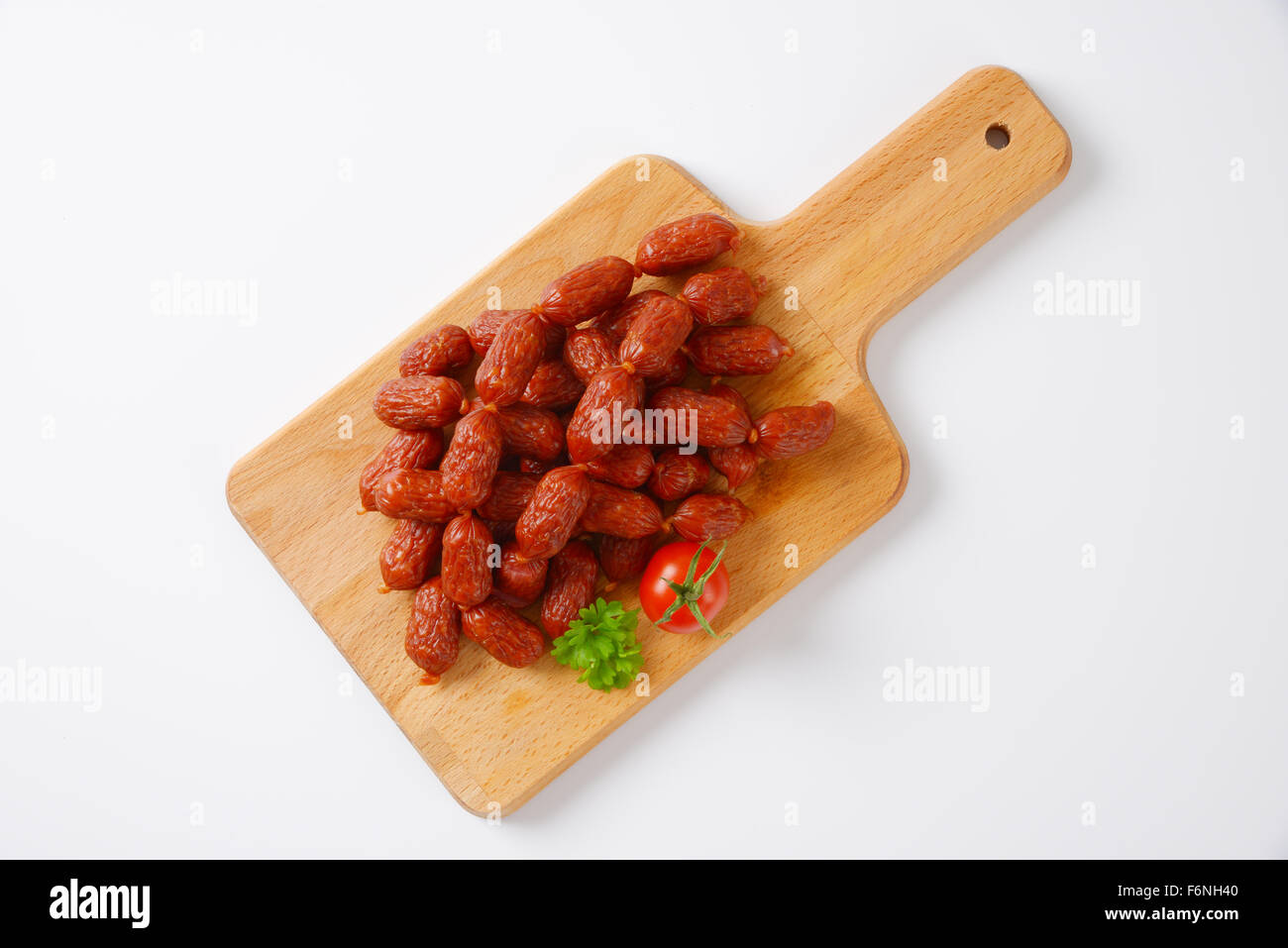 chain of mini sausages on wooden cutting board Stock Photo