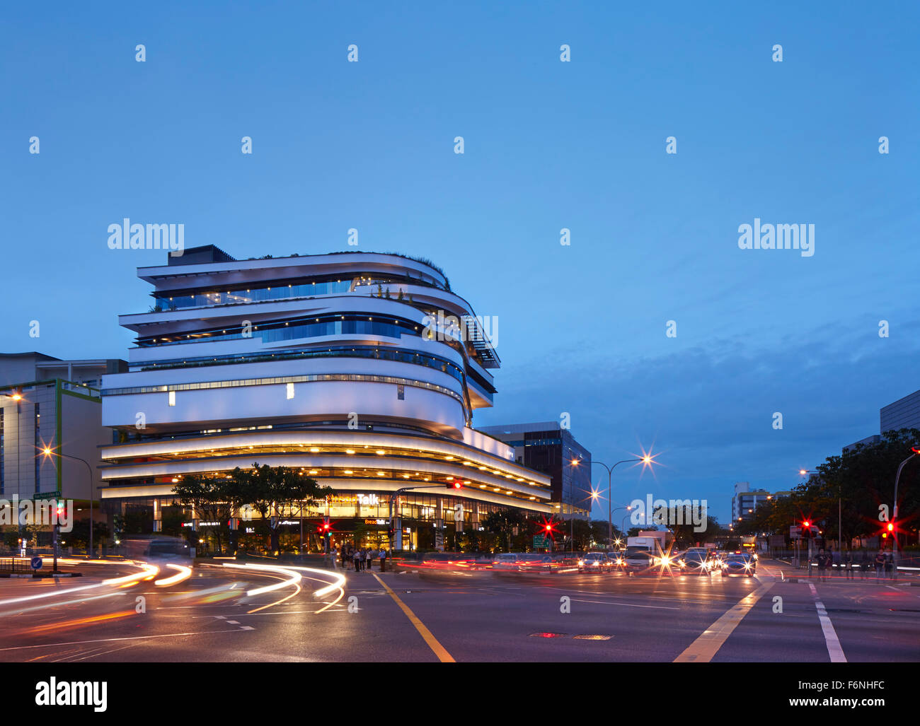 Exterior elevation across busy intersection at dusk. BreadTalk IHQ, Singapore, Singapore. Architect: Kay Ngeee Tan Architects, 2 Stock Photo