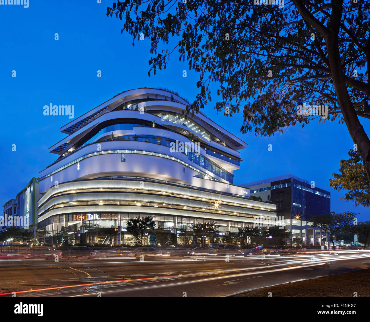Night elevation across street with light trails. BreadTalk IHQ, Singapore, Singapore. Architect: Kay Ngeee Tan Architects, 2014. Stock Photo