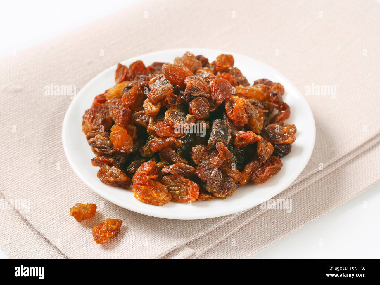 plate of raisins on beige place mat Stock Photo
